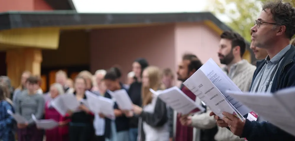 Menschen die in einer Reihe stehen und einen Zettel in der Hand halten, den sie lesen.